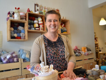 Delphine Vacher pose au milieu des fils et pelotes de laines dans la recyclerie Au petit grenier