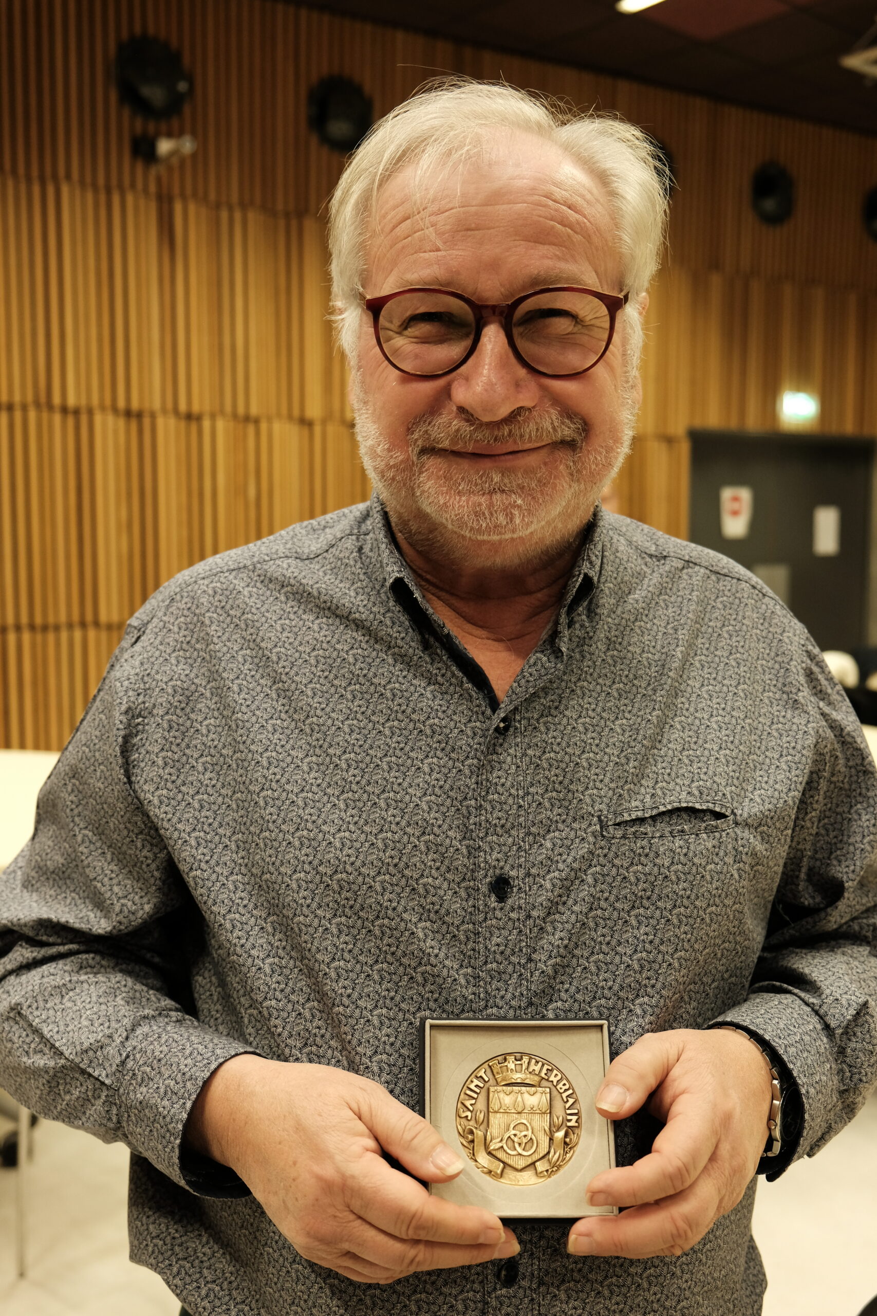 Gérard Royer souriant tient la médaille de la Ville de Saint-Herblain dans ses mains.