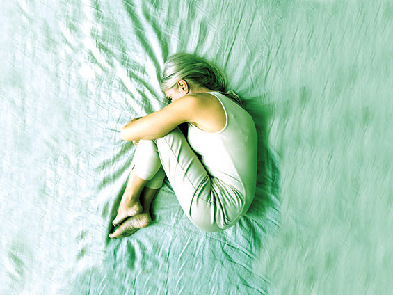Une femme est allongée en position fœtale sur un drap.
