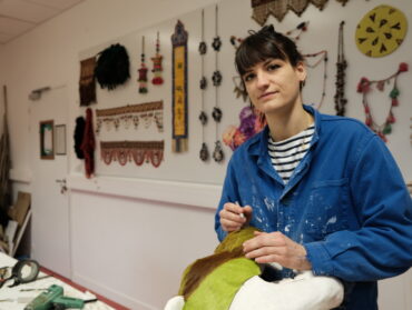 Charlotte Caron est en train de fixer une peau de chèvre vert fluo sur un tête de panthère en résine.