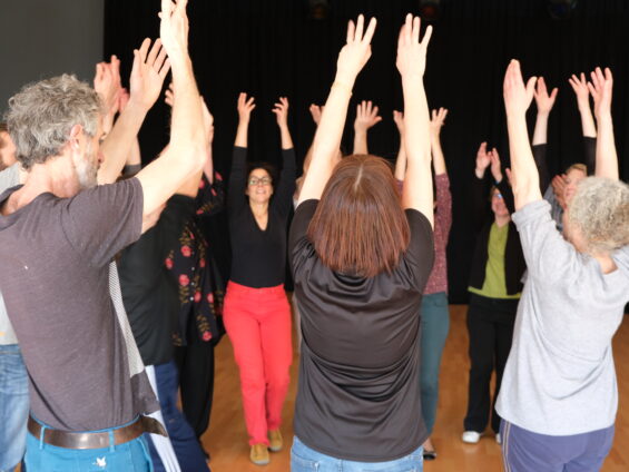 Les danseuses et danseurs apprennent des danses du monde. ici ils lèvent les bras et forment une ronde.