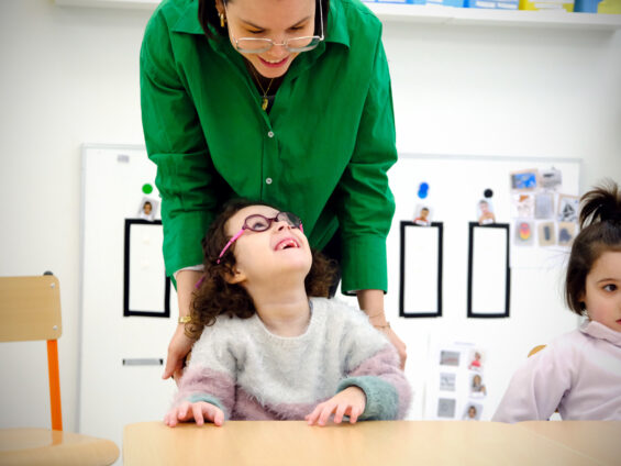 Un jeune enfant atteint d'autisme regarde en souriant son éducatrice de la crèche de l'Orée des pins