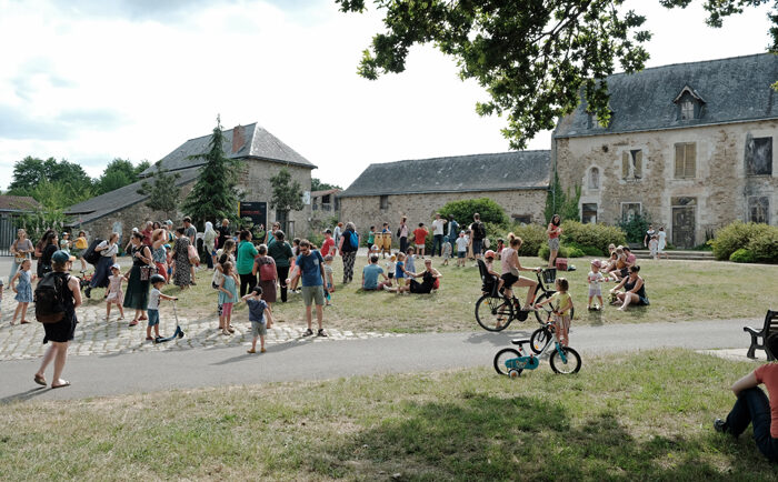 Une petite foule d’enfants et d'adultes est réunie devant les bâtiments du domaine de la Bégraisière pour écouter un concert.