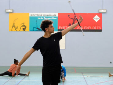 Medhi Hatchane s'entraine au gymnase de la Bernardière, en arrière plan des twirleuses plus jeunes font des exercices au sol.