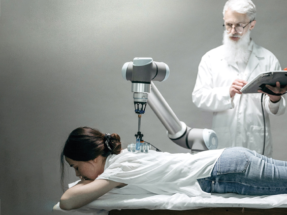 Un vieil homme en blouse blanche observe, une tablette numérique à la main, une jeune femme allongée sur une table d'examen, examinée par un bras articulé.