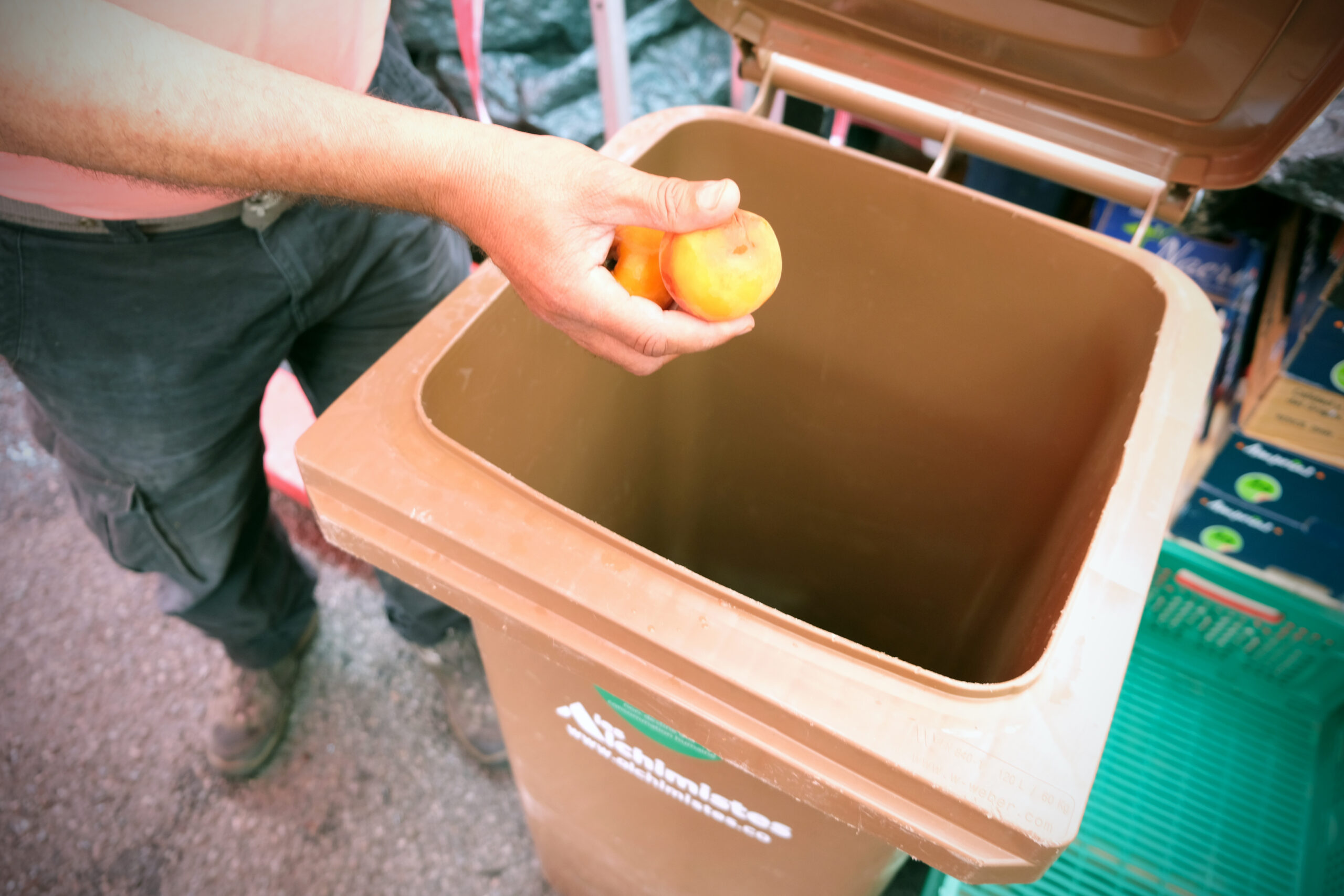 Un commerçant du marché de Bellevue dépose des fruits inconsommables dans une poubelle dédiée à la récolte des biodéchets