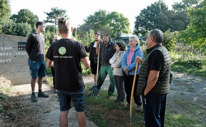 Un maître-composteur de l’association Compostri explique aux participants habillés en tenue de jardin comment composter en tas.