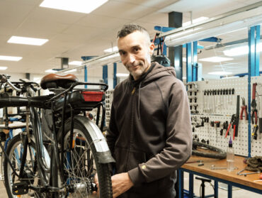 Karim Benferchiche intervient sur un vélo électrique dans l'atelier d'ATAO.