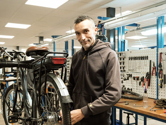 Karim Benferchiche intervient sur un vélo électrique dans l'atelier d'ATAO.