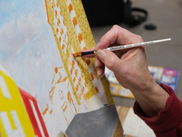 Une main utilise un pinceau fin pour peindre un tableau.