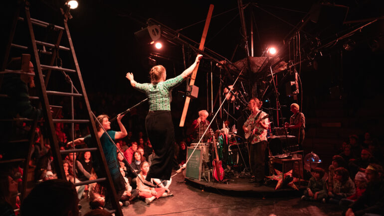Des musciens jouent de la guitare tandis qu'une femme est en équilibre sur un fil. Un spectacle du Collectif Surnatural à voir pendant les Beaux Jours.