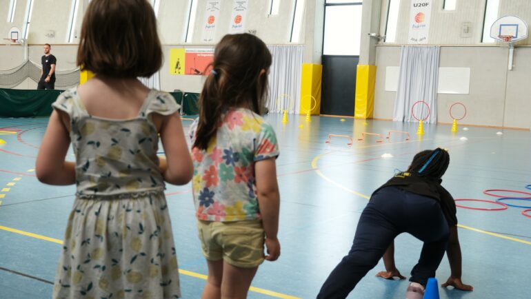 Des enfants sont dans un gymnase et se préparent à une course en relai.