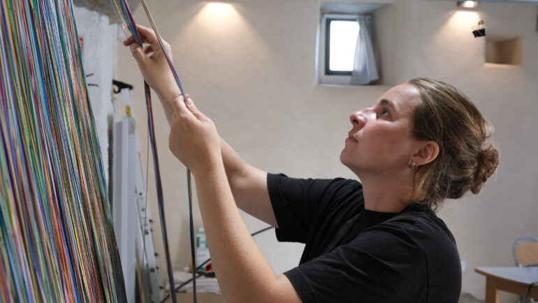 L'artiste Julie Maquet démêle des centaines de fibres optiques avec lesquelles elles va réaliser une œuvre tissée