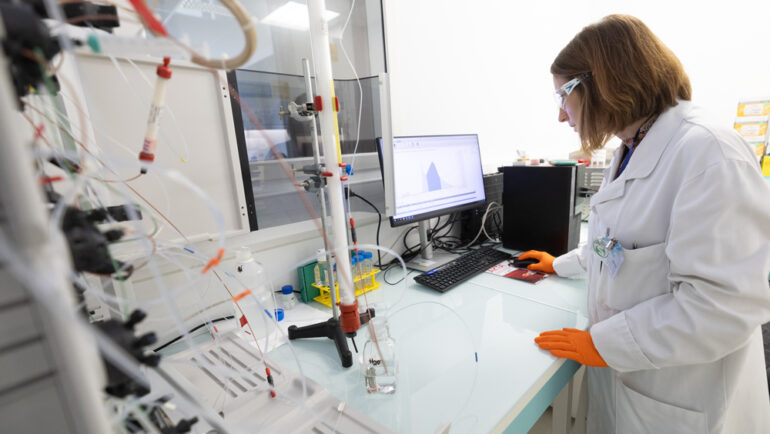 Une technicienne observe des résultats sur un écran d'ordinateur dans un laboratoire immaculé.