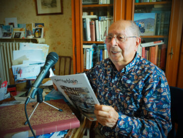 Michel Aknin tient le magazine de la Ville de Saint-Herblain devant son micro.
