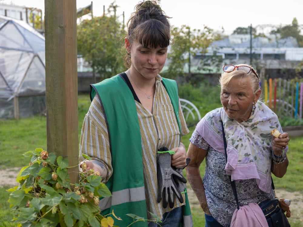 Une animatrice d’Environnements solidaires montre une plante à une habitante dans la petite ferme urbaine