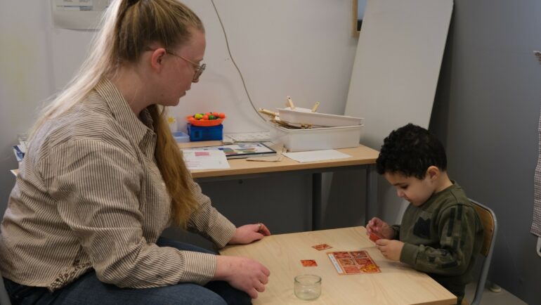 l'enseignante de lUEMA se trouve face à un élève. Ils travaillent ensemble autour d'une table.