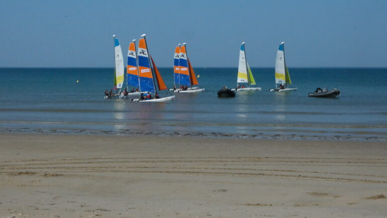 Des catamarans voguent sur l'océan. La scène se passe en Vendée, sur une plage de Notre-Dame-de-Monts.