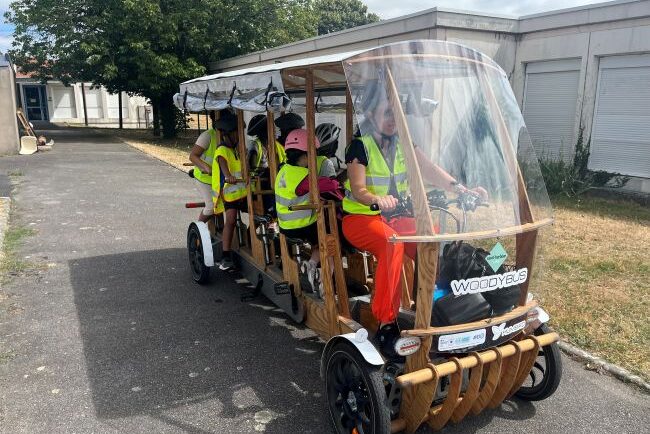 Des enfants ont pris place dans le woodybus et prennent le chemin de l'école